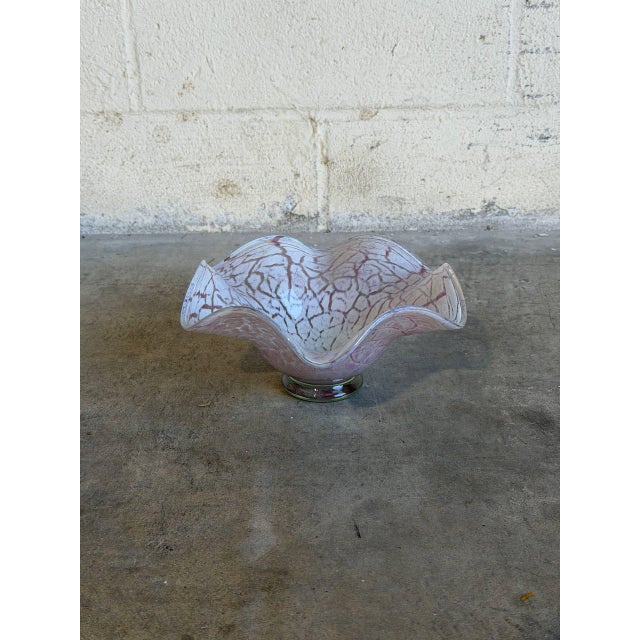 This exquisite art glass centerpiece bowl features a dramatic, undulating ruffled rim resembling a flower in full bloom....