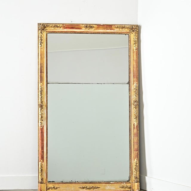 This French Empire mantle mirror (early 1800s) exhibits restrained surface decoration concentrated to intermittent, low-...