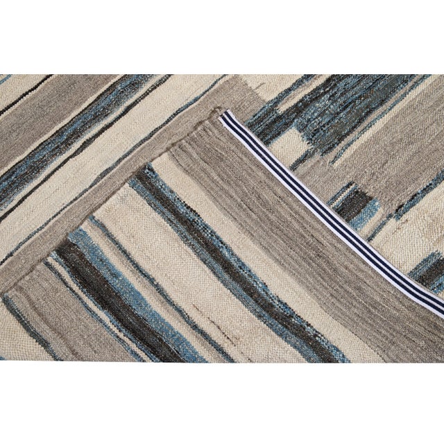 Beautiful Modern flat-weave handmade wool rug. This Kilim rug has a beige field with accents of blue and brown in a...