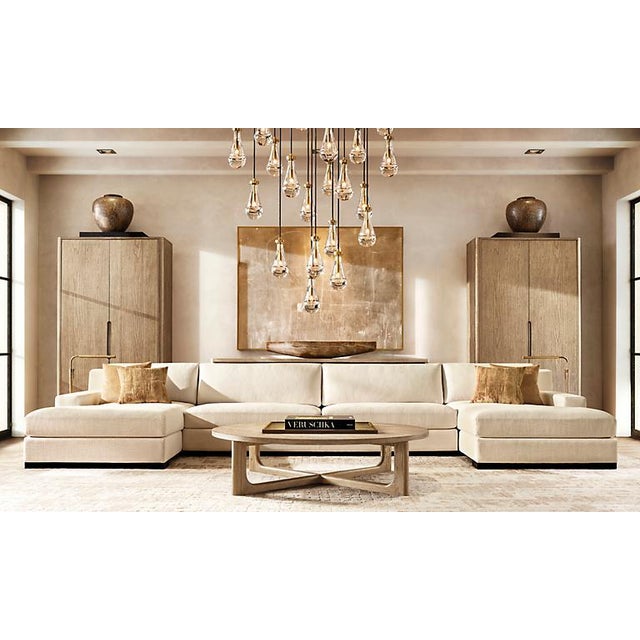 Constructed from individually hand-blown solid glass drops, solid brass fittings, and suspended black fabric cords, the RH...