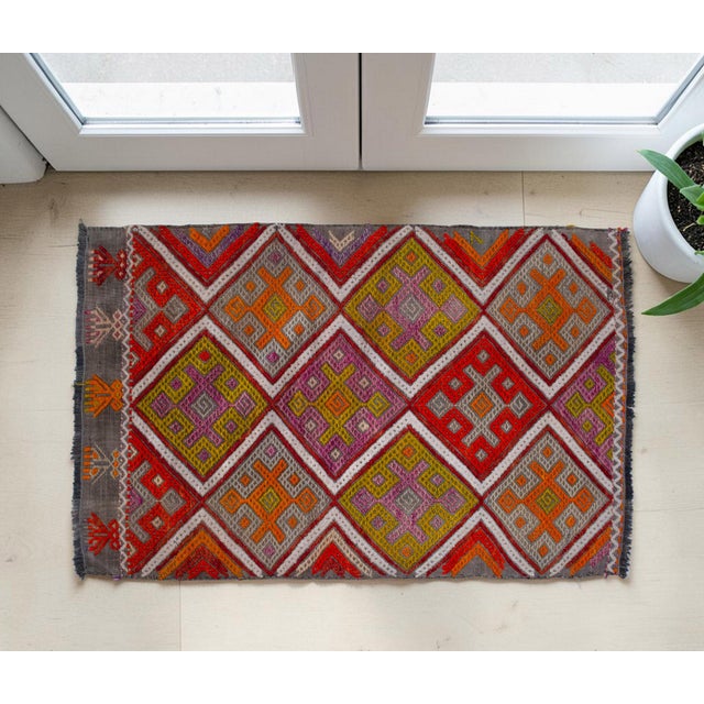 This hand-woven small rug captures the effortless elegance of Anatolian flat-weave artistry, blending vibrant geometry...