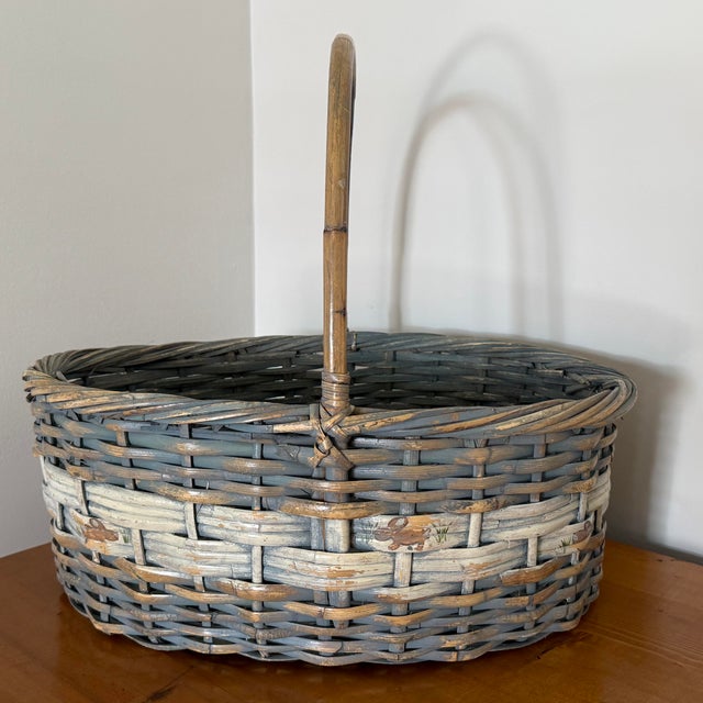 Large vintage gathering basket with a tall bentwood handle and a distressed gray-blue finish. A cream woven band shows...