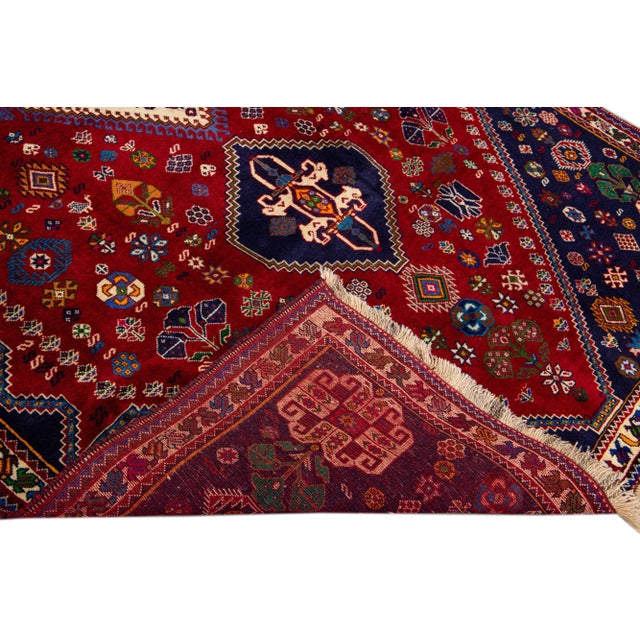 Beautiful Vintage Shiraz hand-knotted Wool rug with the red field. This Shiraz rug has a multicolor accents in all over...