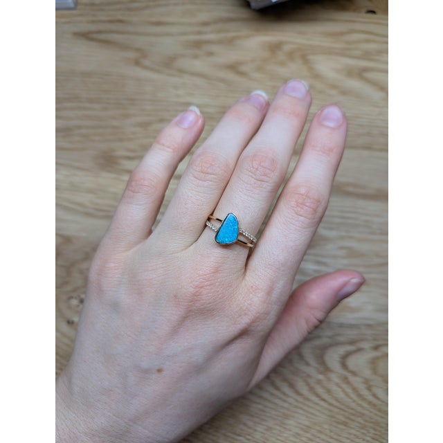 A 1.62 carat Boulder Opal with an organically irregular shape takes center stage in this 14K yellow gold ring. The bezel...