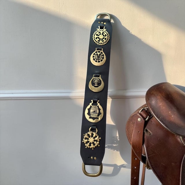 A handsome vintage English horse brass martingale featuring five solid brass horse brasses mounted on a wide black leather...