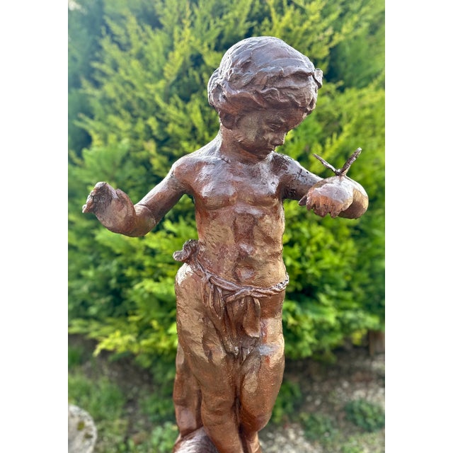 An elegant cast iron garden statue depicting a little girl watching a butterfly perched on her hand. A scene full of...