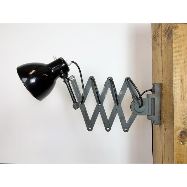 This vintage Industrial adjustable scissor wall lamp was produced in former Czechoslovakia during the 1950s. The lamp has...
