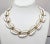 This is part of Chairish’s Costume Jewelry assortment. Goldtone and white textured resin links collar necklace with hook...