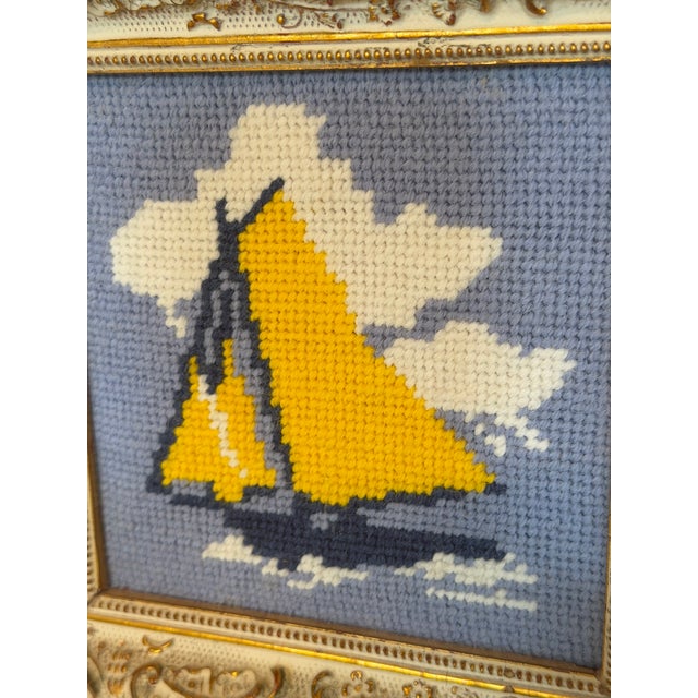 Charming vintage needlepoint depicting a classic sailboat gliding across the water beneath billowing white clouds. The...