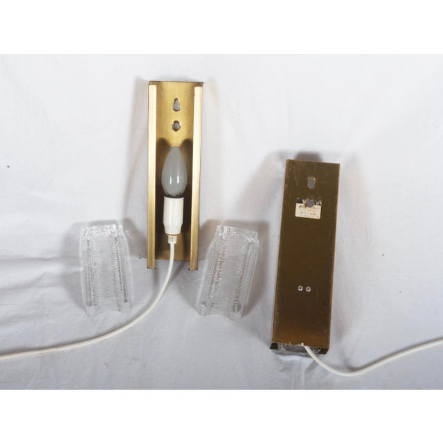 This pair of sconces features brass constructions with pressed glass elements fitted with E14 sockets. It was made in...