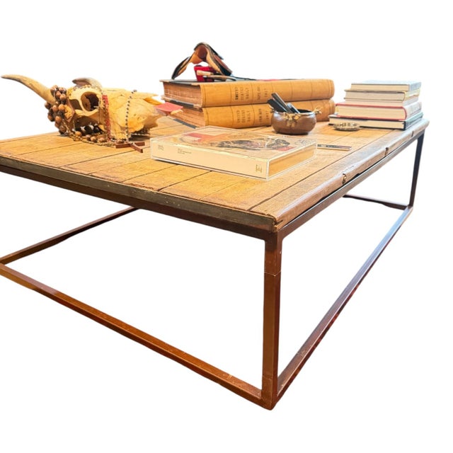 A substantial Restoration Hardware “Bookmaker” coffee table featuring a reclaimed plank-style wood top set within a...