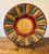 This wall hanging showcases a meticulous arrangement of mosaic-like segments, creating a striking radial pattern that...