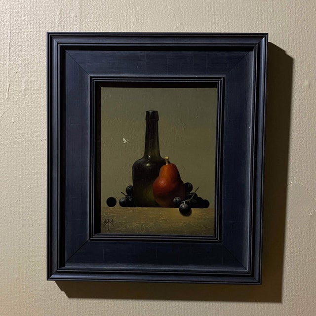 The composition features a striking still life with a dark green bottle, a vibrant red Anjou pear, and clusters of deep...