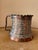 This Persian tankard is crafted from copper and tin. It features a fluted top and intricate, traditional floral and bird...