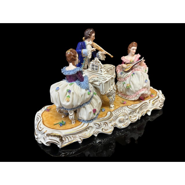 A porcelain grouping featuring three 18th figures at a piano. Backstamped with the Volkstedt mark to the underside...