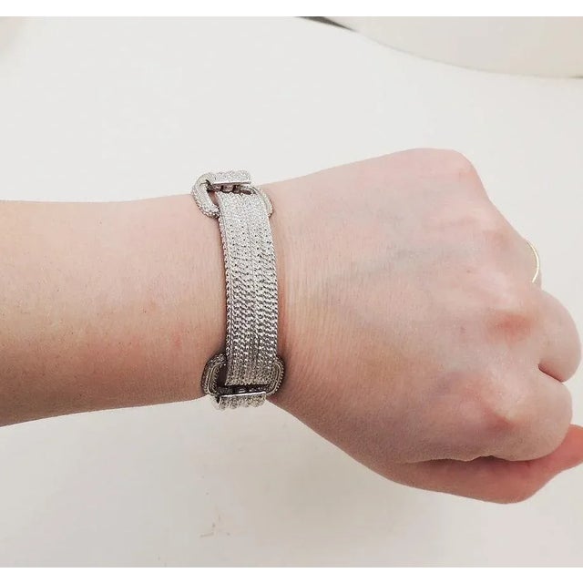 This is part of Chairish’s Costume Jewelry assortment. 1970s rhodium plated buckle bracelet with fold over clasp and...