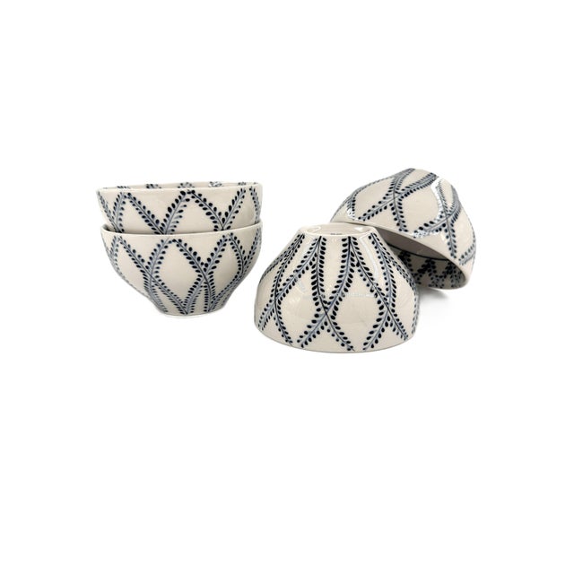 A beautifully set of four hand-painted ceramic bowls from Bat Trang, Vietnam, featuring a rhythmic indigo botanical...