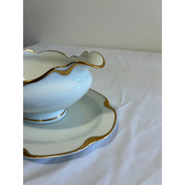 An elegant antique gravy boat by Haviland & Co. Limoges, featuring a scalloped wavy rim with hand-applied gold trim and a...