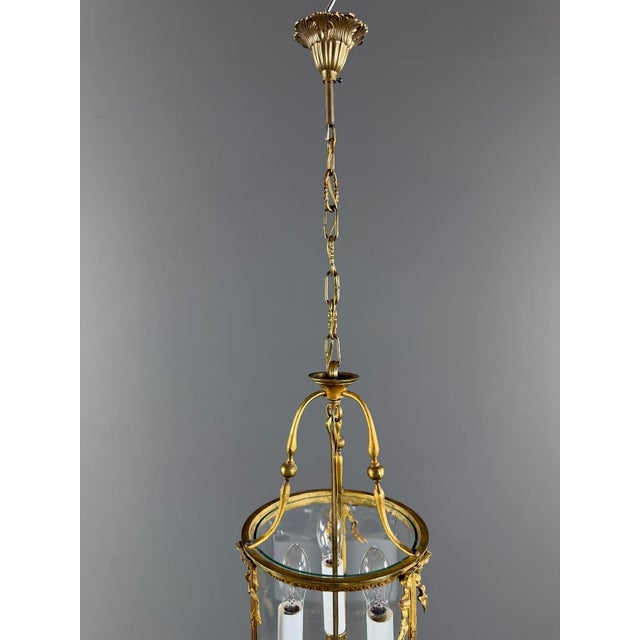 Elegant cylindrical lantern in gilt bronze, adorned with finely chiseled motifs of foliage, ribbons, and pearls. The...