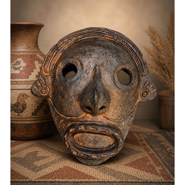 A wonderfully sculptural vintage Peruvian pottery mask with an expressive elongated face and richly textured, smoke-...