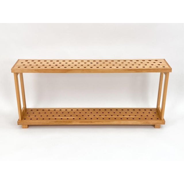 A long narrow cane and walking stick display case or storage rack with two-tiers of maple wooden racks with two horizontal...