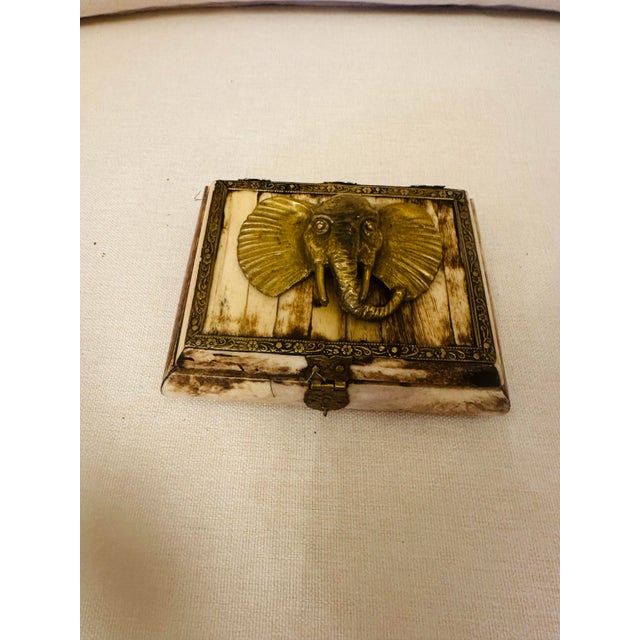 A striking decorative keepsake box clad in natural bone panels and accented with ornate brass trim and hardware. The lid...