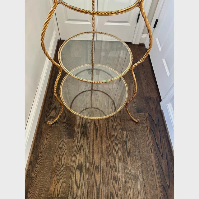 Gorgeous vintage Italian Hollywood Regency style gilt metal / tole etagere. With four tiers and glass shelves, this piece...