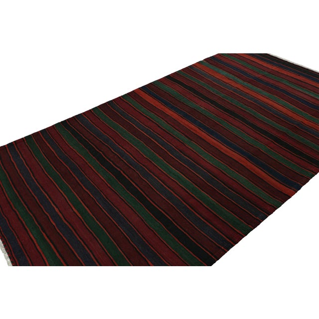 Handwoven in wool, circa 1950-1960, this 5x9 vintage Afghan tribal kilim rug in Burgundy, is an exciting new curation in...