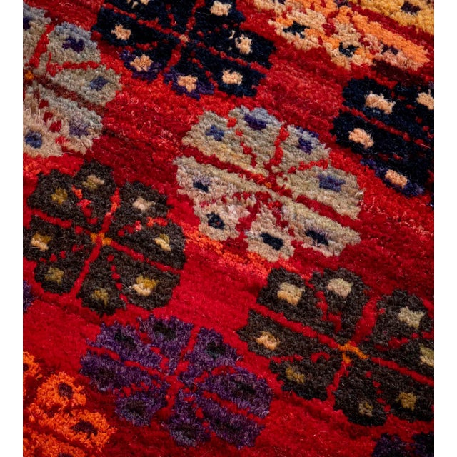 This vintage handwoven wool Turkish rug has a shaded tomato-red field with horizontal bands of polychrome stylized floral...