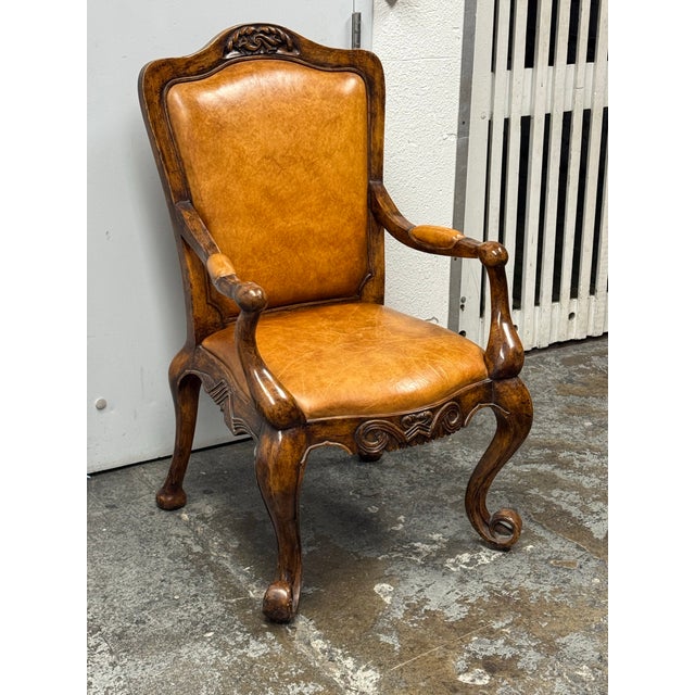 Design Plus Gallery presents a Vintage Venetian Leather Carved Wood Armchair. The armchair showcases an ornate wood frame...