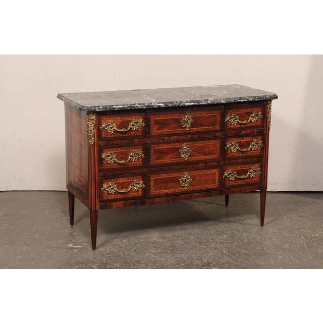 A French marble top commode, with beautiful inlay, book-match veneers and rococo style hardware, from the 19th century....