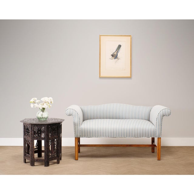 A handsome upholstered mahogany diminutive settee or window bench crafted in a Georgian era Chippendale style measuring...