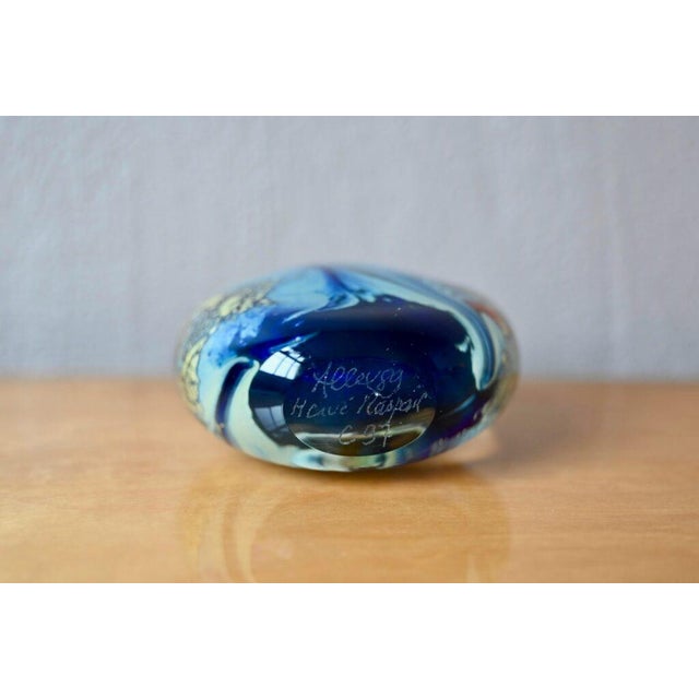 This small, flat, spherical bottle is made of blown glass. Its predominantly blue decoration is rich with multicolored and...