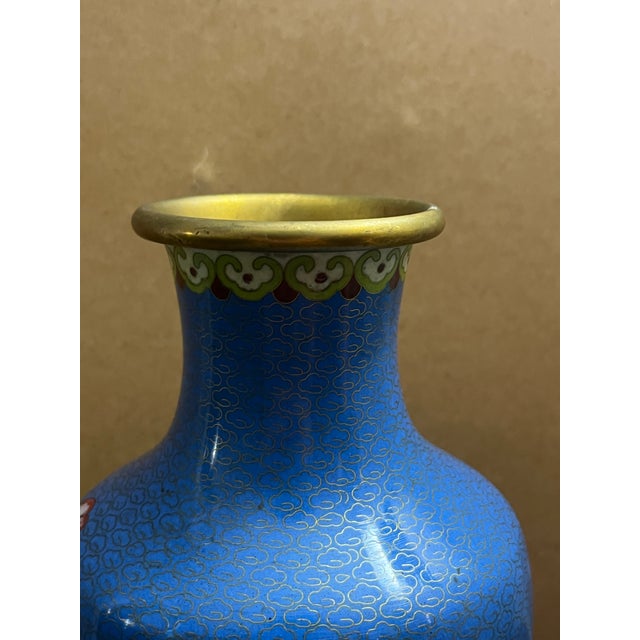 A vintage Chinese cloisonné vase handcrafted over a brass body with a vibrant cobalt blue ground featuring a delicate...