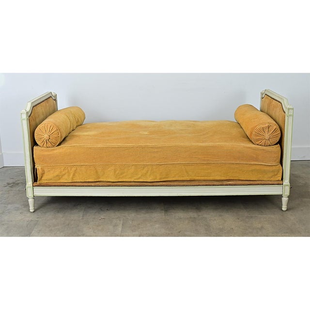 A lovely 19th-century French daybed crafted in the Louis XVI style. The wooden bedframe has a painted finish that has...