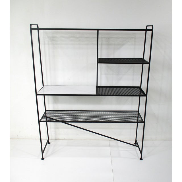 A very well crafted satin black metal framed bookcase etagere with perforated shelves and one in wood having a white...