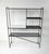 A very well crafted satin black metal framed bookcase etagere with perforated shelves and one in wood having a white...