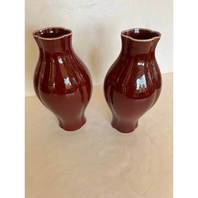 Fetching pair of glossy glazed ox blood color ceramic vases having a lovely scalloped top and bottom.