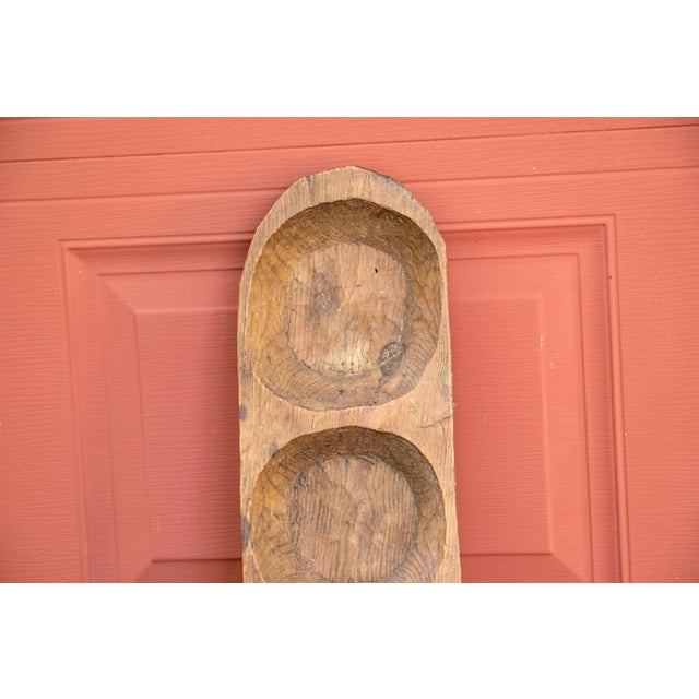 A long, primitive carved wooden dough bowl with heavily weathered patina and fitted with a series of eight round hollowed...