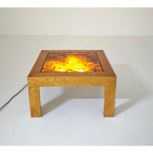 A vintage and modernist coffee table featuring a square solid wood frame with a built-in backlit acrylic glass top. The...