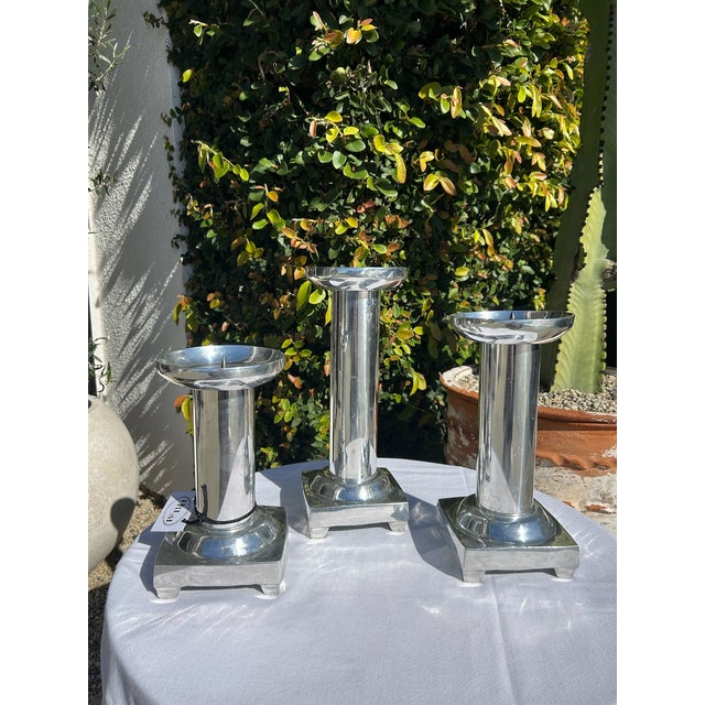 Set of three vintage pewter silver candle holders featuring tiered pedestal bases and wide circular top plates. Graduated...