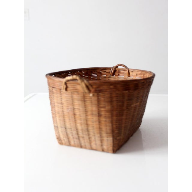 A vintage woven rattan basket with a wonderfully structured rectangular form and small loop handles at each end. The fine...