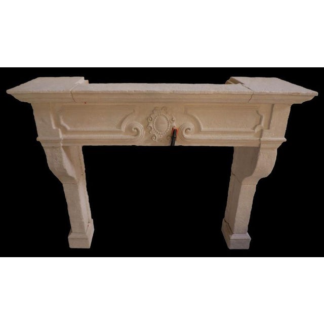 A striking French Louis XIV style fireplace mantel crafted in limestone during the 20th century. This piece showcases a...