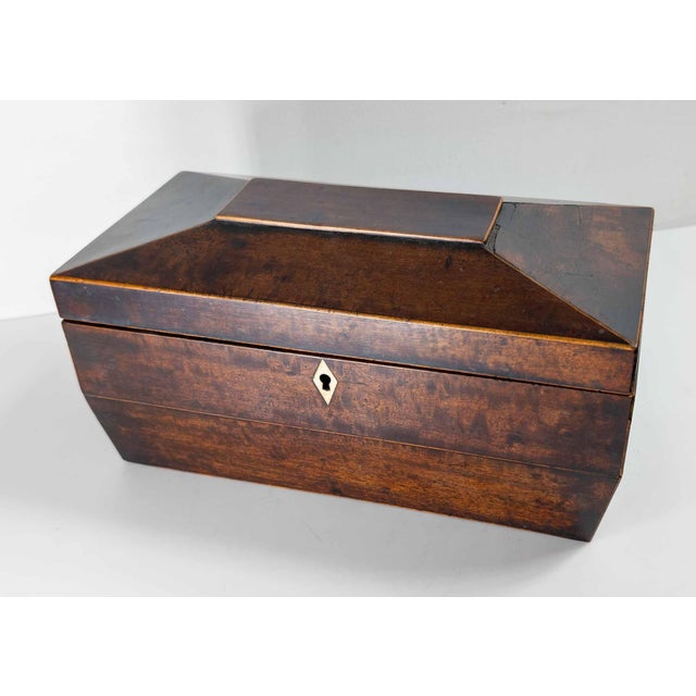 We are selling this mahogany veneered English Regency sarcophagus form tea caddy. This nice tea caddy has simple form with...