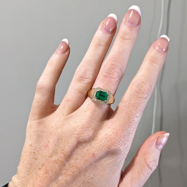This beautiful east west ring features a 1.67 carat emerald cut Emerald gemstone with a halo of natural earth mined...
