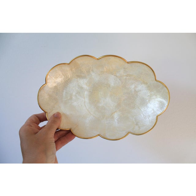 Set of two Capiz shell shallow trinket trays with scalloped gold tone edges. Set also includes two coasters. No makers...