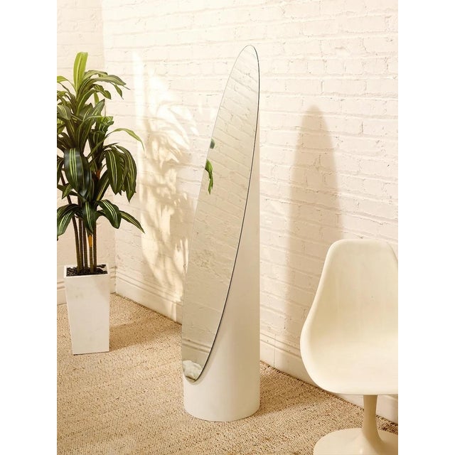 A playful postmodern floor mirror with a tall, elongated silhouette and a curving frame that gives the piece its...