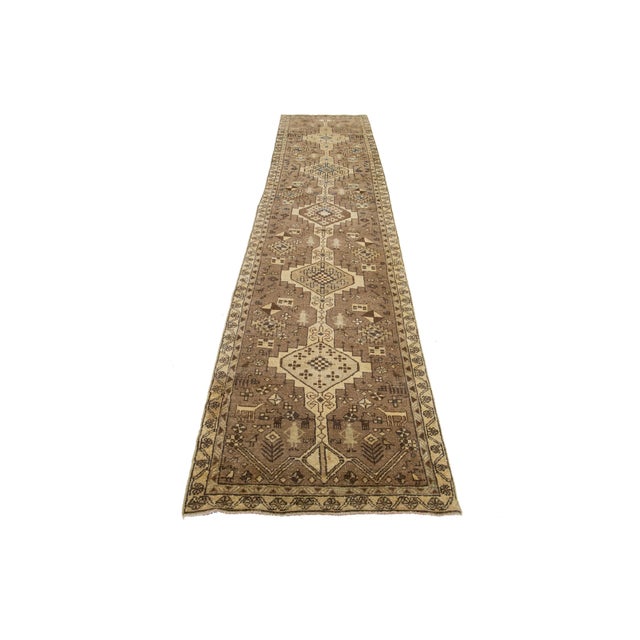 This vintage wool runner features a brown field with beige and blue tribal accents of Persian origin. This rug measures...