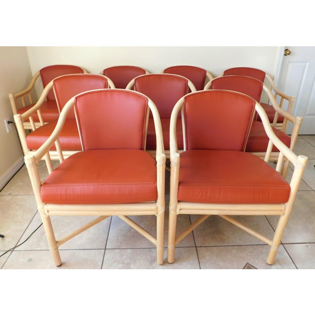 Wonderful set of nine McGuire rattan and cane club chairs. Rust colored vinyl upholstery. Leather wrapped. Each one has...