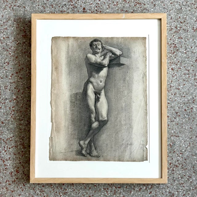 This charcoal study captures a nude male figure in quiet contemplation, his body turned in profile with one arm resting...